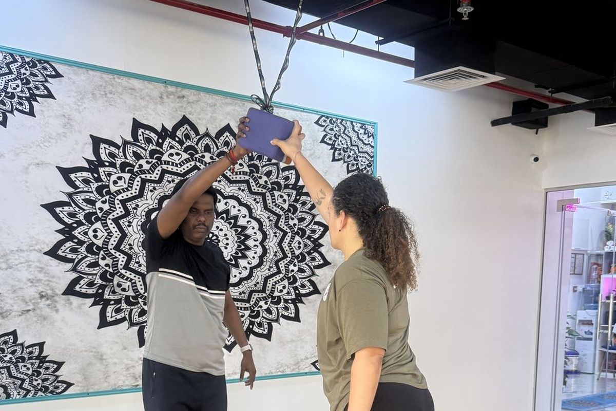Dr. Kasi guiding a student's alignment with a yoga block at the Thousand Petaled Lotus studio